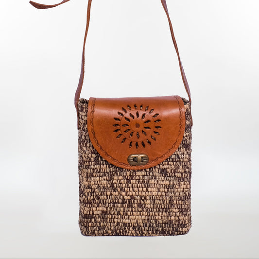 Dark raffia crossbody pouch with decorative cutout leather flap and antique metal twist lock