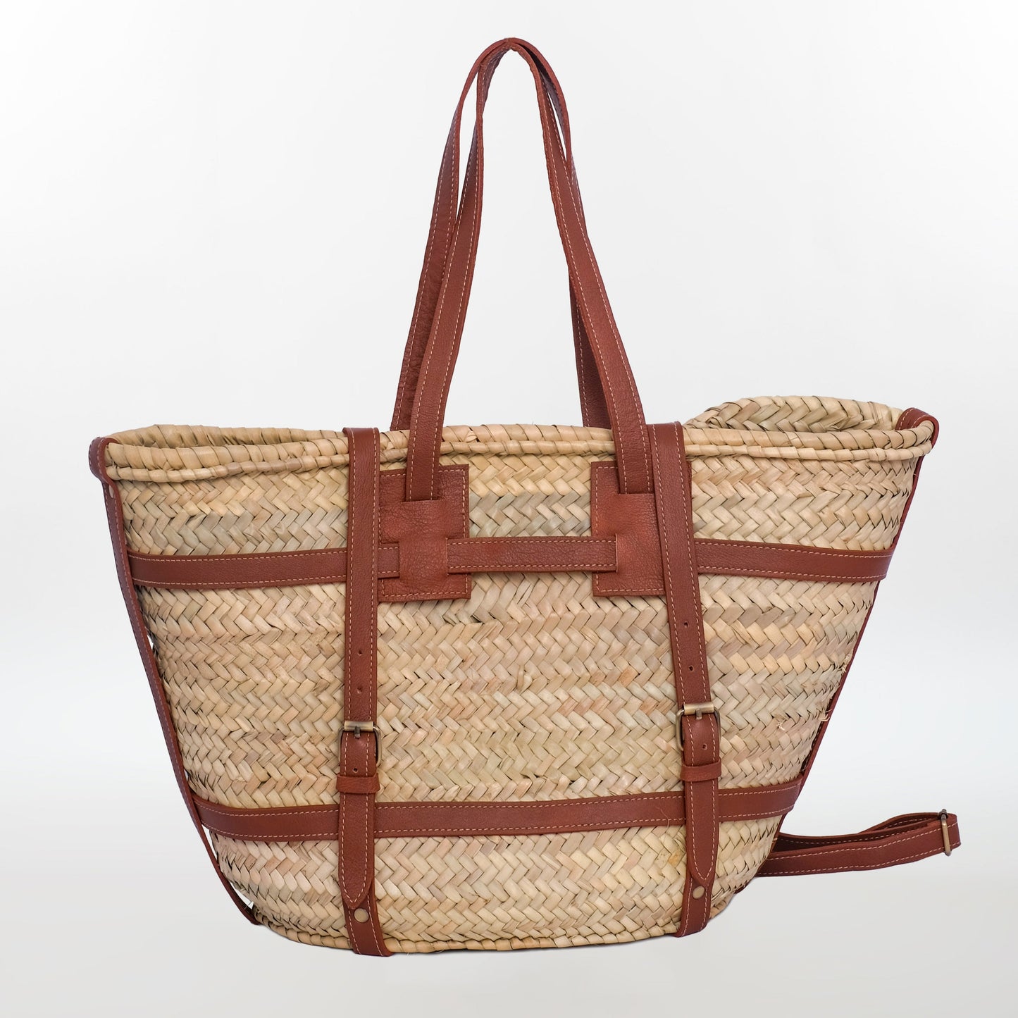 Handwoven Moroccan straw tote bag with brown leather straps and buckles