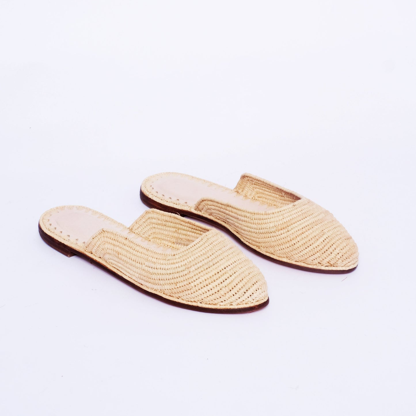Women’s handmade pointed-toe raffia mules in natural color with flat leather sole and artisan Moroccan construction.