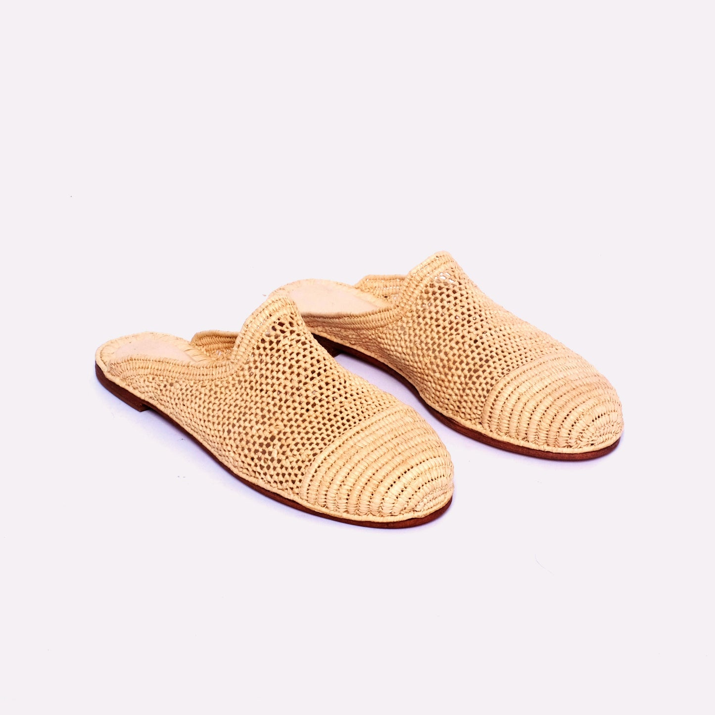 Handwoven raffia mules with mesh body and solid woven toe cap, flat leather sole, slip-on design, handmade in Morocco.