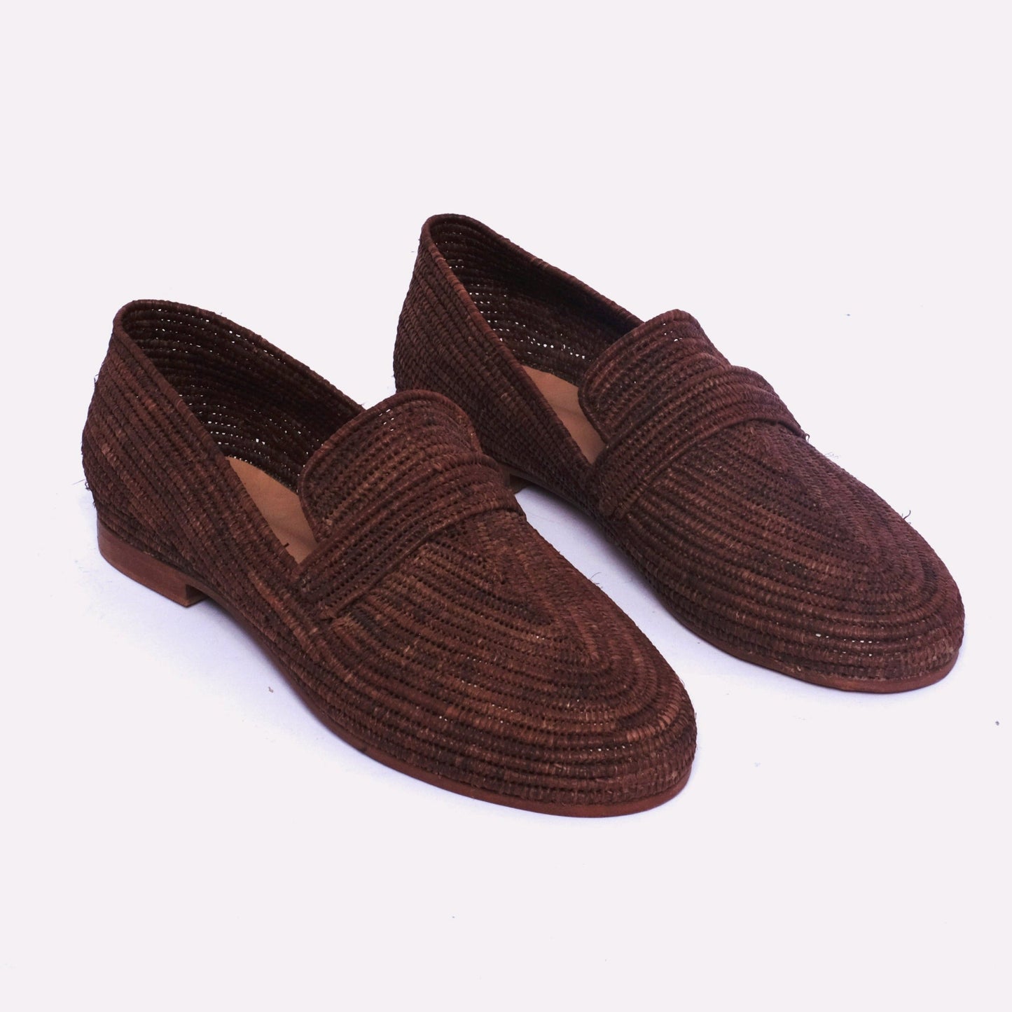 Women’s loafers made from dark brown raffia, handwoven in Morocco with a leather sole and clean loafer silhouette.
