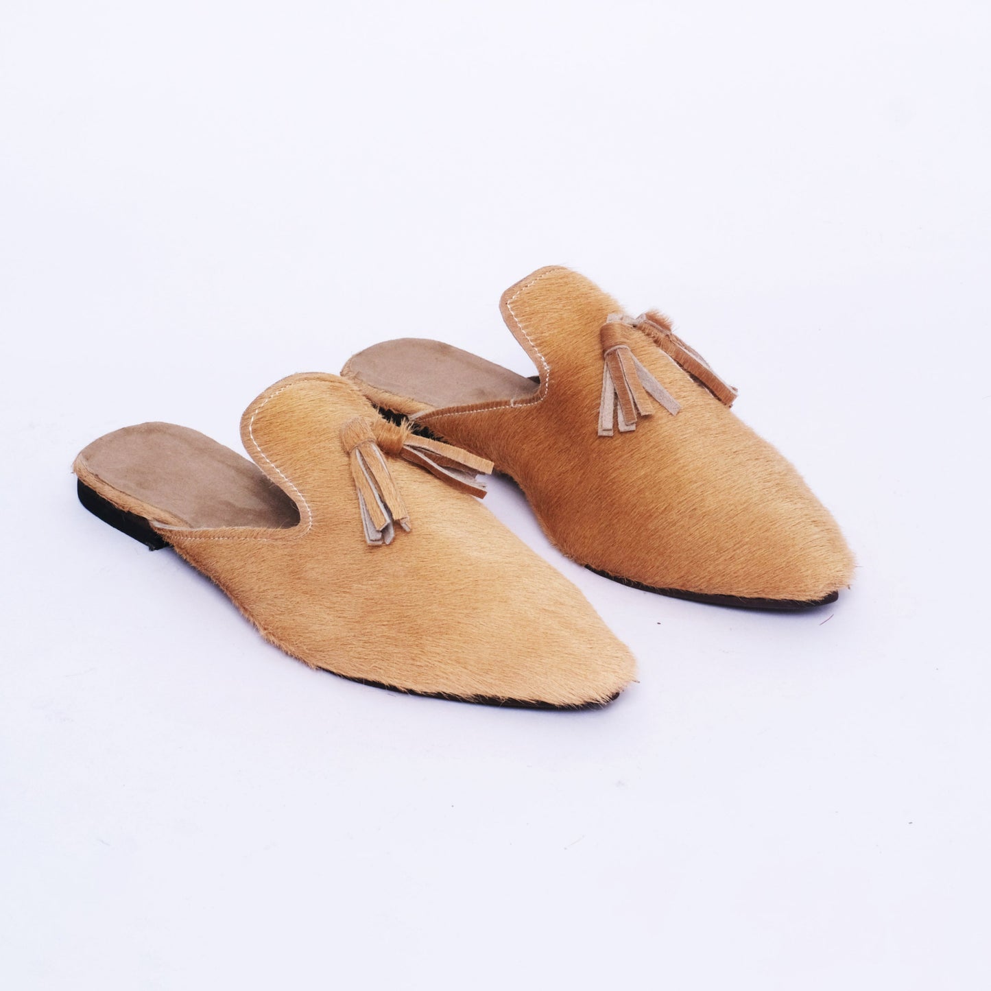 Women’s handmade slip-on mules with natural hair-on leather upper, pointed toe, and leather tassel detail, crafted in Morocco.