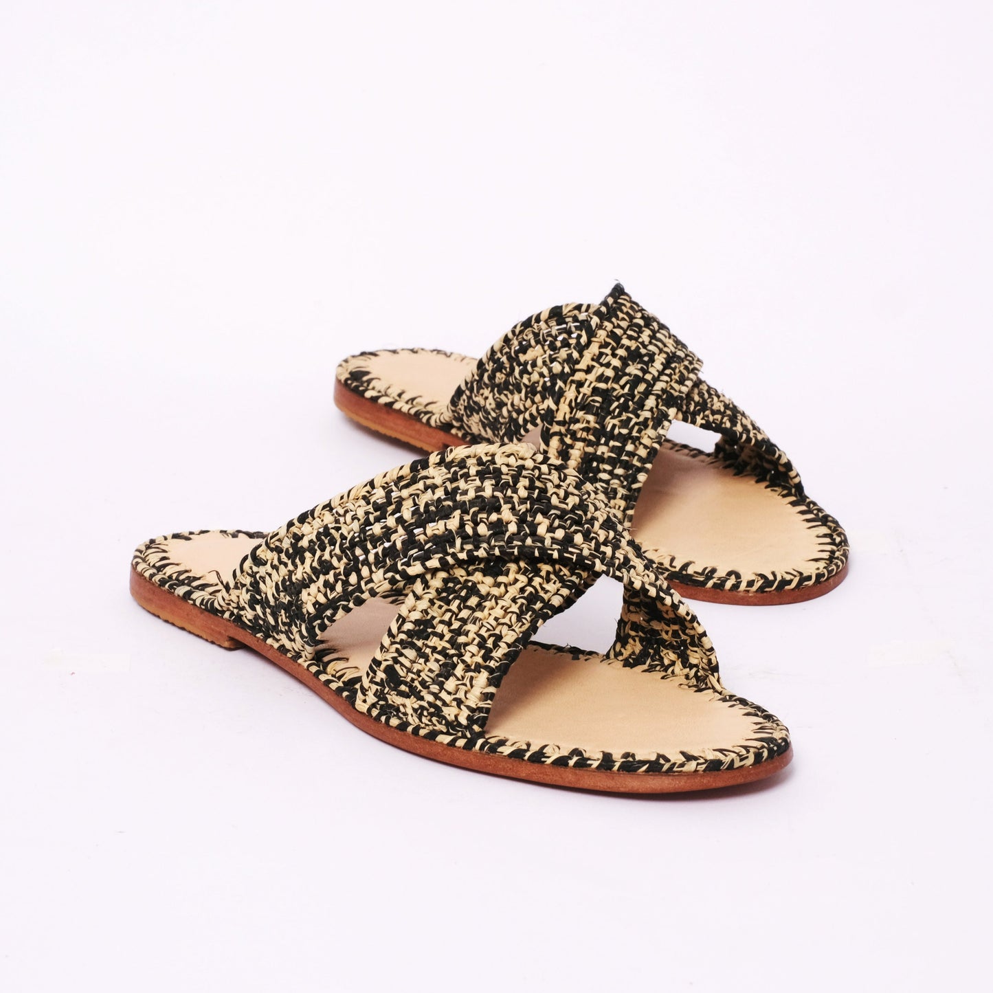 Flat raffia sandals with black and beige handwoven cross straps and leather sole