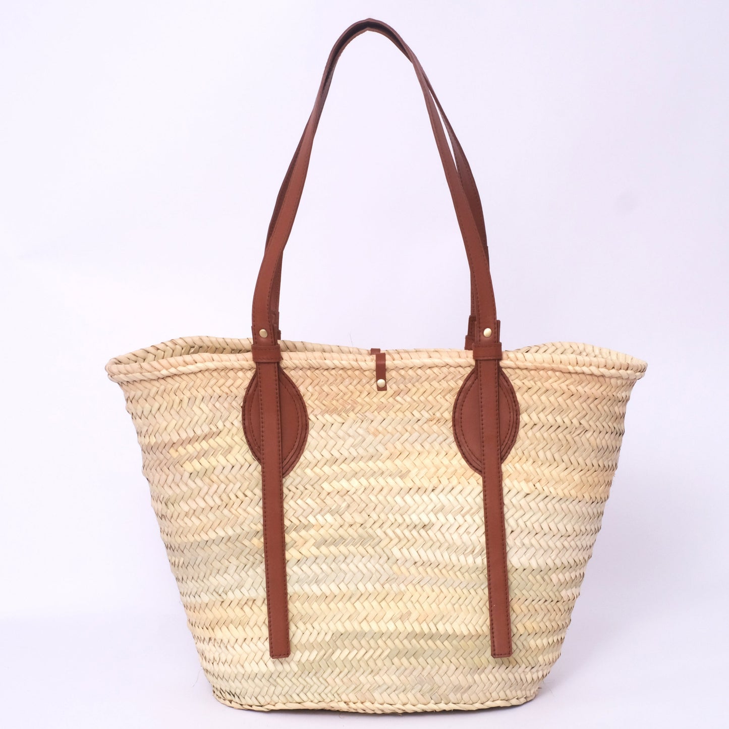 Moroccan straw tote bag with long brown leather straps and oval leather reinforcements, photographed on a white background.