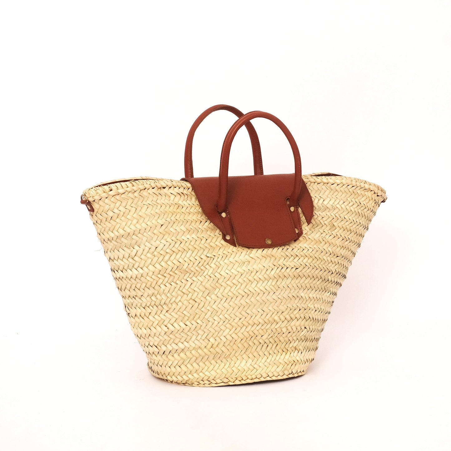 Handwoven Moroccan straw tote bag with brown leather flap and dual handles, photographed on a white background.