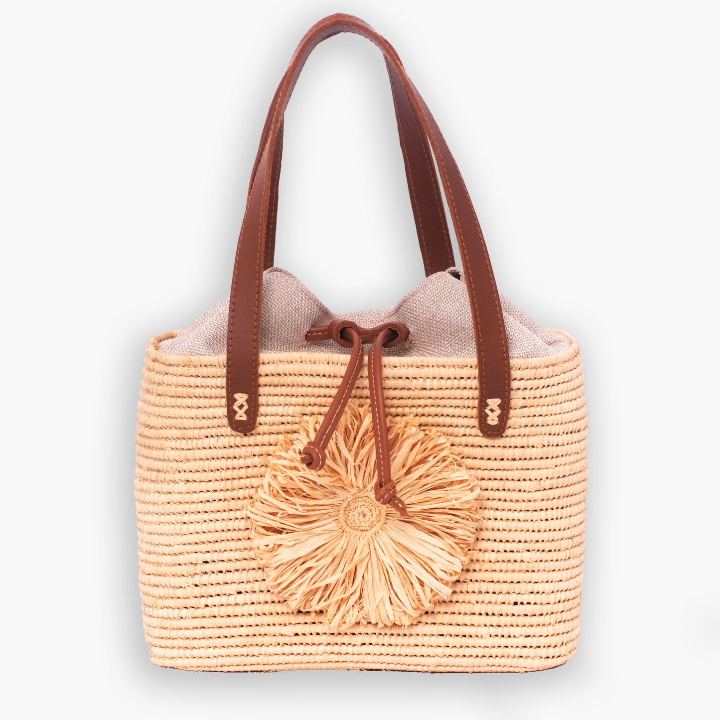 Handwoven raffia tote bag with leather handles, drawstring linen top, and raffia flower accent
