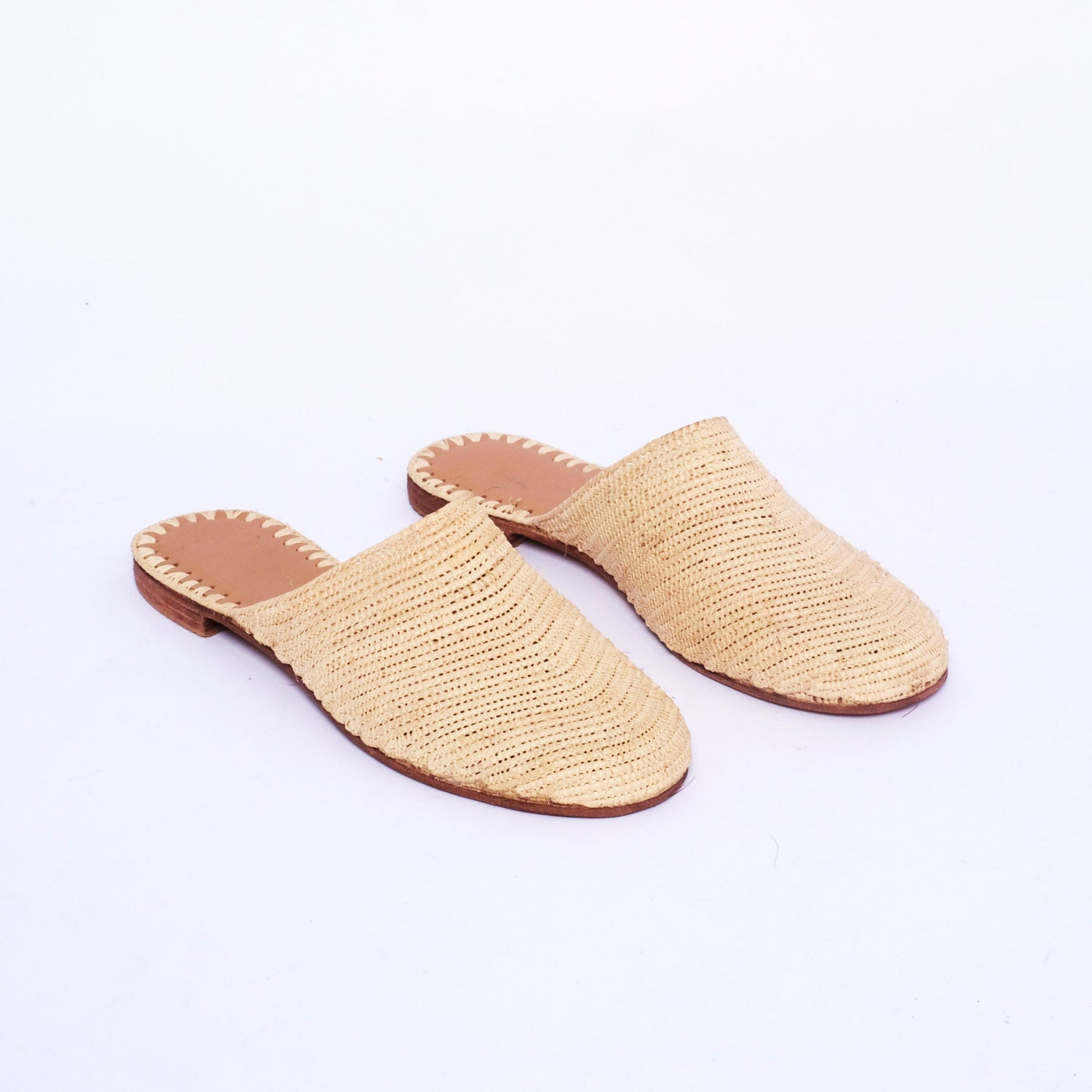 Handmade Moroccan raffia mules with natural woven uppers and leather soles, photographed on a white background.