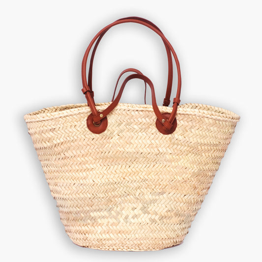 Classic Moroccan straw tote bag with round leather anchor patches and double-loop handles, photographed on white background.