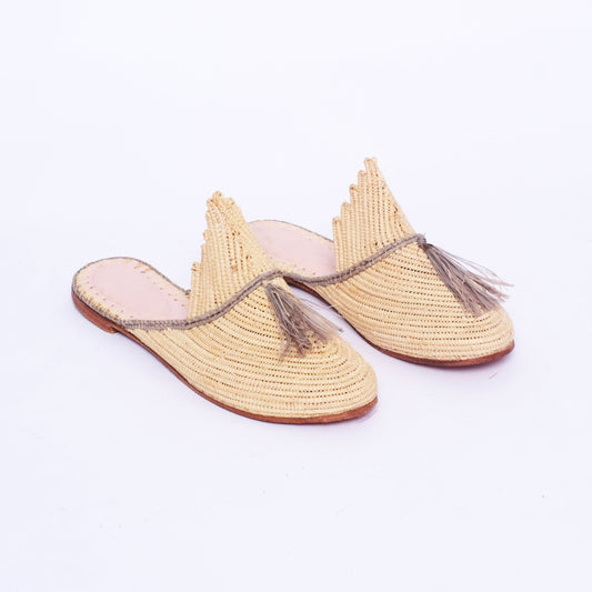 Handwoven Moroccan raffia mules in natural with grey tassel and trim, featuring scalloped tongue, leather sole, and slip-on design.