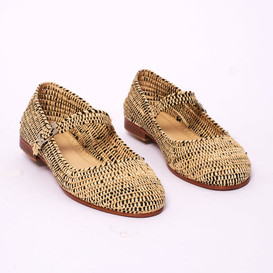 Handwoven women’s Mary Jane flats made from black and natural raffia, featuring a two-tone woven design, leather sole, and adjustable strap, handmade in Morocco.