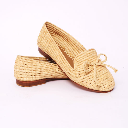 Handwoven women’s raffia loafers in natural color with a raffia bow on the front, flat leather sole, and artisan detailing, handmade in Morocco.