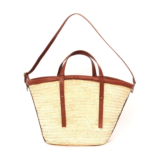 Natural straw carryall with short leather handles and long adjustable shoulder strap, shown against a white background.